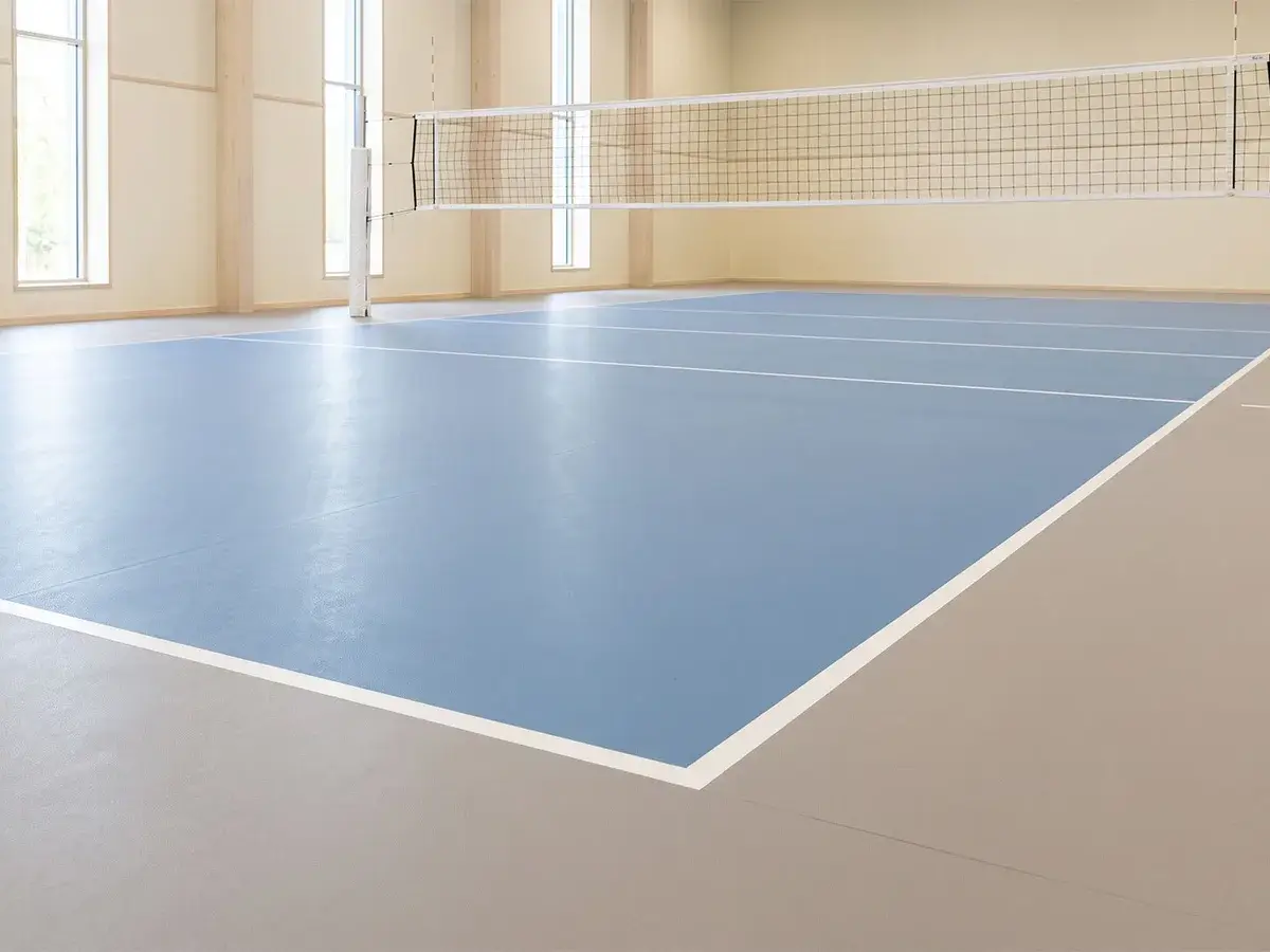 mat, soluk mavi bir oyun alanı ve sıcak gri çevre zeminli kapalı voleybol sahası
